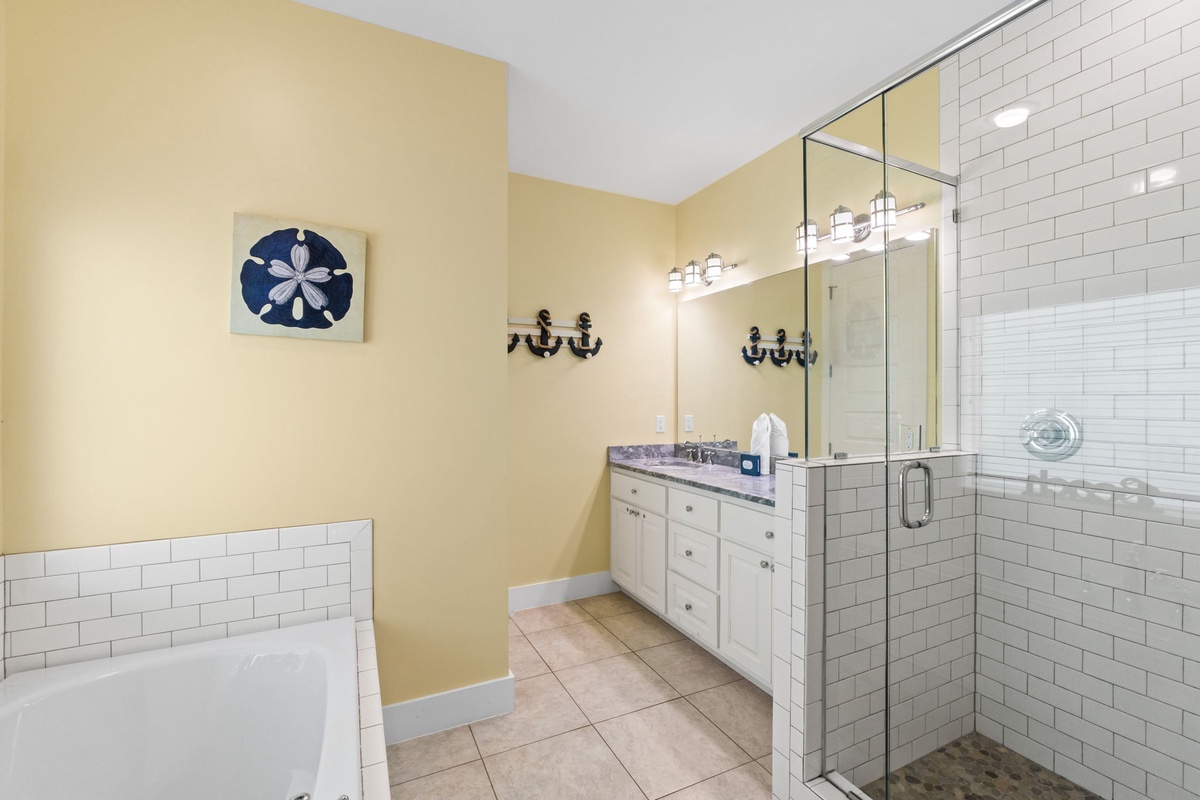 Unwind in your coastal-themed bathroom featuring a luxurious soaking tub, spacious glass shower, and charming nautical touches.