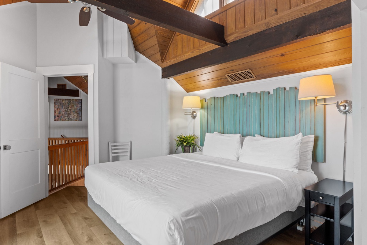 Drift off under soaring wooden beams and a unique driftwood-style headboard. Your plush bed and warm lighting create a coastal-chic retreat.