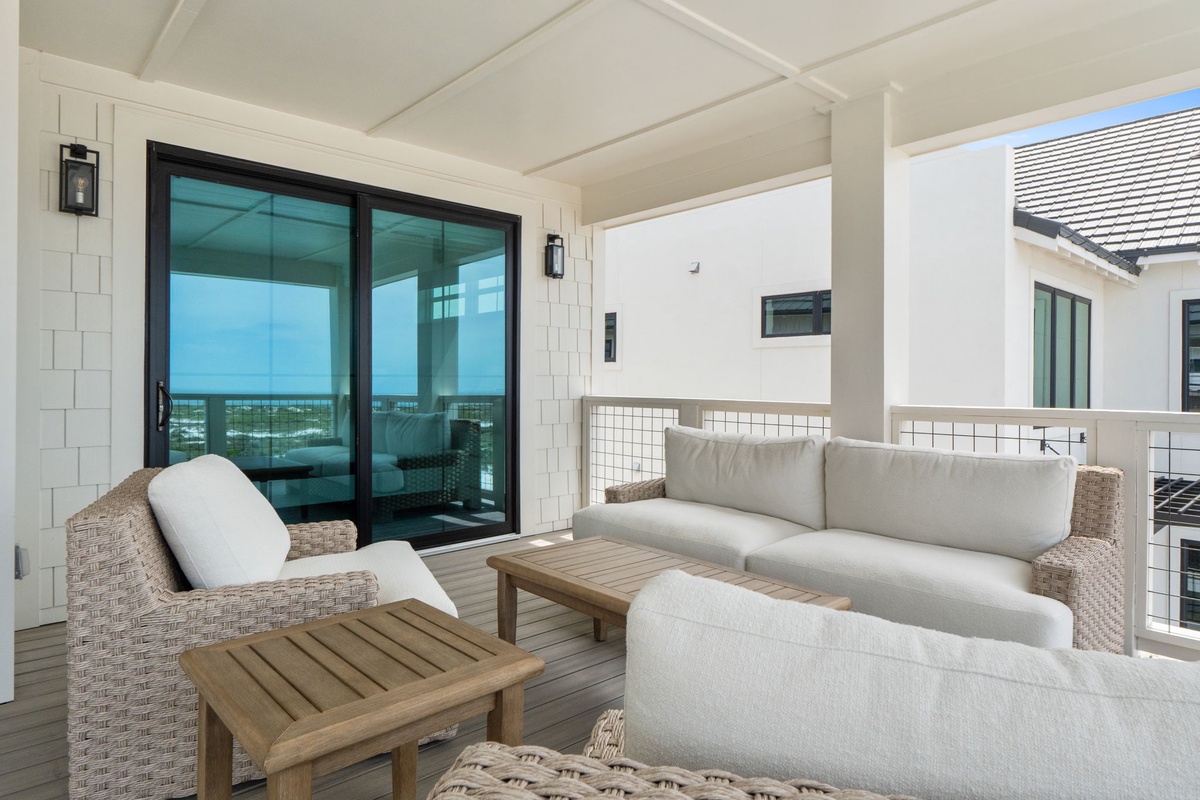 Step onto your private balcony where plush woven seating invites you to unwind with ocean breezes and stunning water views, your perfect coastal retreat.