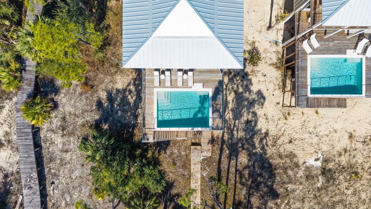 Striking aerial view of a modern beach property featuring pristine swimming pools set among tropical vegetation.