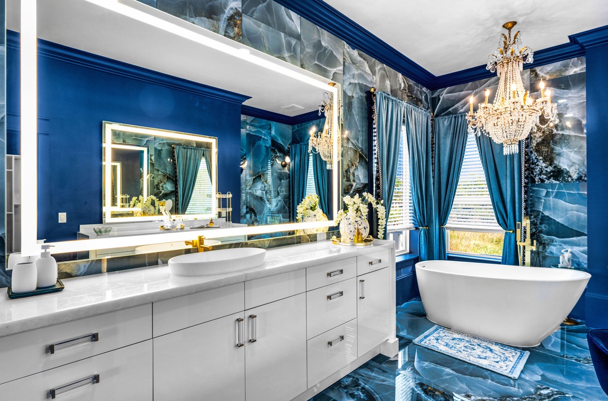 Luxurious bathroom with elegant soaking tub, crystal chandelier, and stunning blue marble creates your perfect spa retreat.