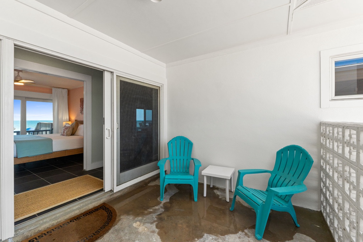 The private balcony awaits with colorful Adirondack chairs perfect for morning coffee or evening cocktails. Peek through to ocean views that beckon from just beyond your cozy coastal bedroom.