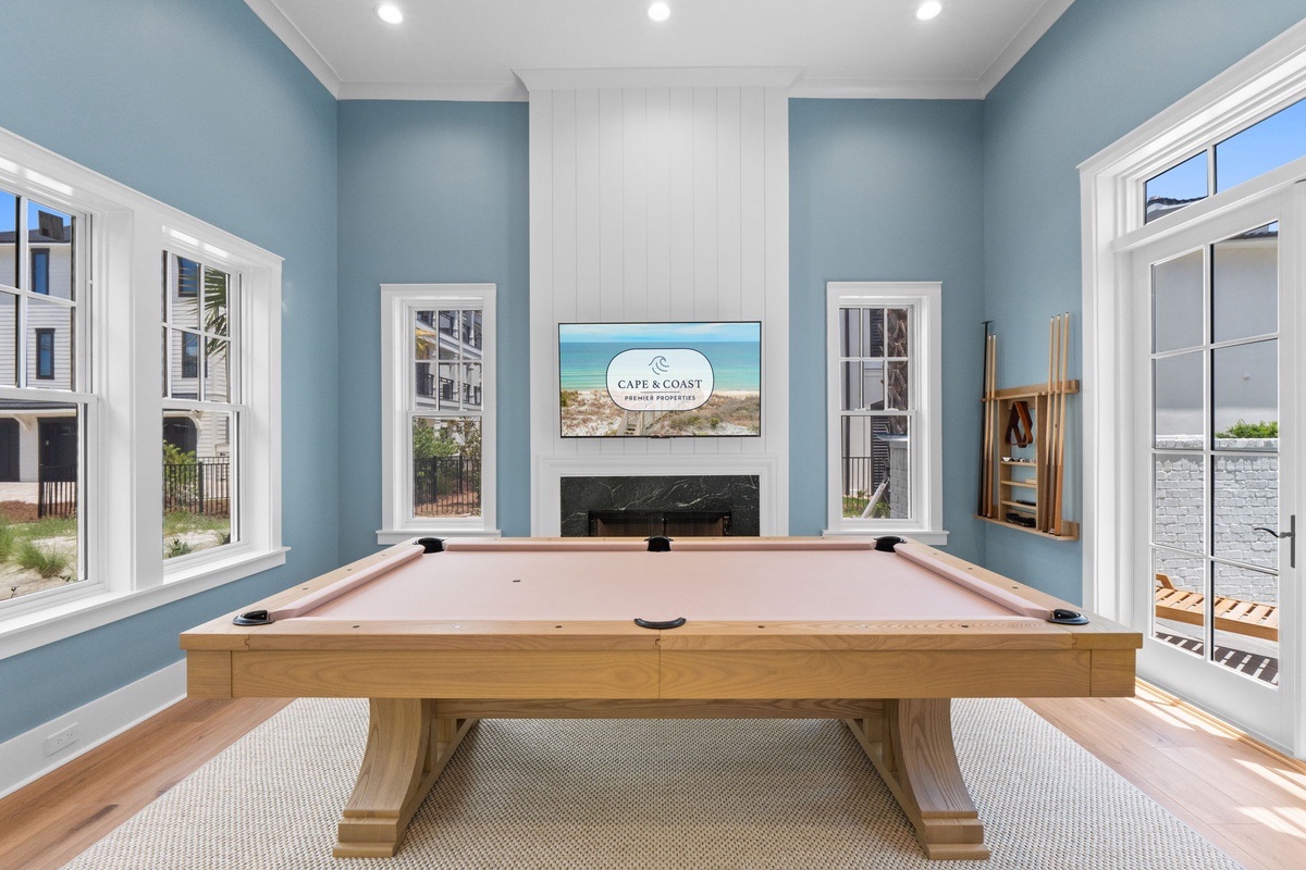 Challenge friends to a game on your private billiard table, framed by coastal blue walls and natural light streaming through elegant windows, creating your perfect retreat for fun and relaxation.