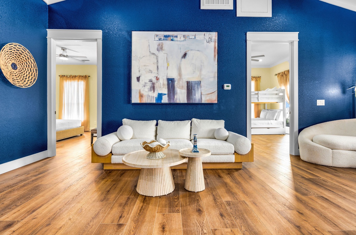Relax in your stylish living space with bold blue walls, warm hardwood floors, and modern furnishings that create the perfect retreat.
