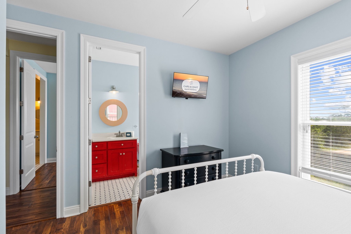 Unwind in your peaceful bedroom with serene blue walls, warm hardwood floors, and an en-suite bath just steps away—your perfect retreat after a day of adventure.
