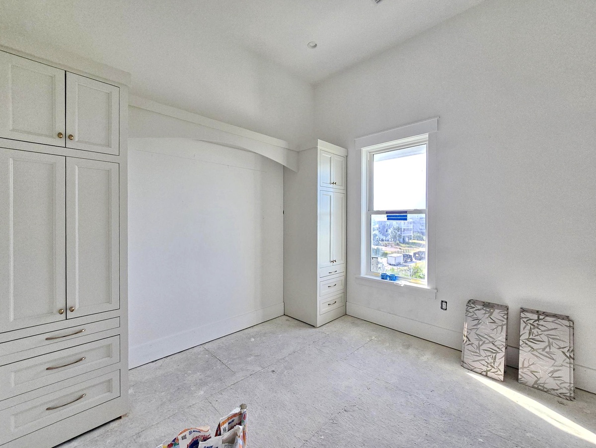 Bright, clean space with built-in storage and crisp white cabinetry ready to welcome you. Natural light pours through the window, offering a glimpse of the surrounding area as you settle in.