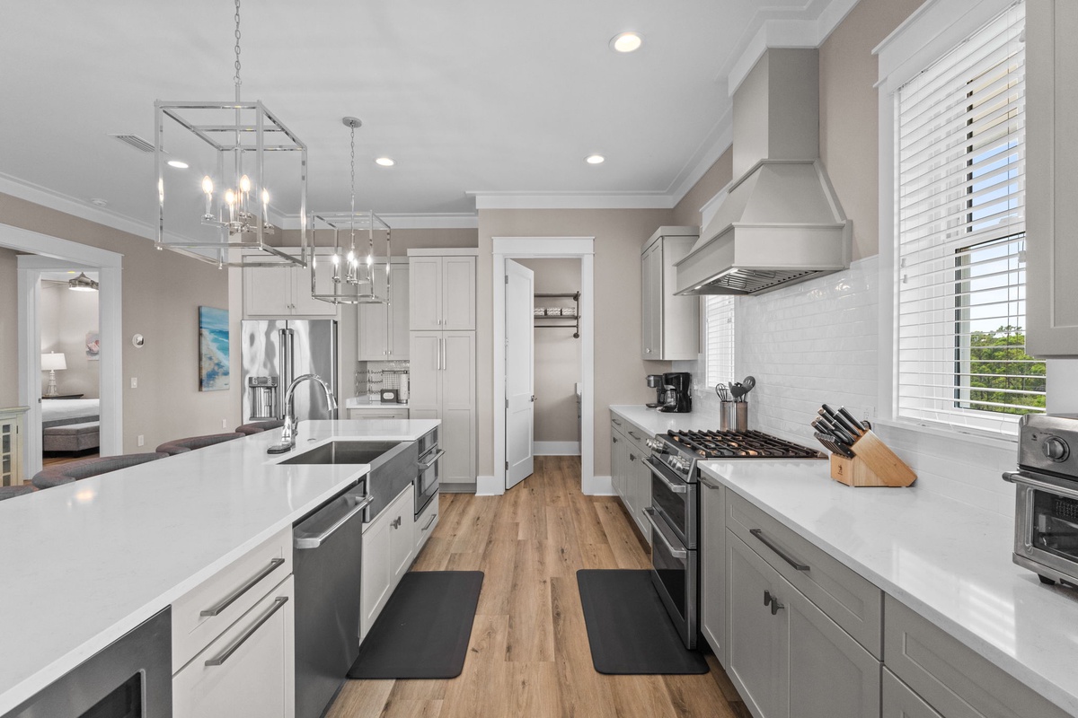 Step into your spacious gourmet kitchen, where gleaming white countertops and modern gray cabinetry create the perfect space for preparing meals and gathering with loved ones during your stay.