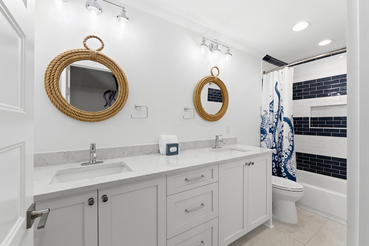Step into your bright, nautical-inspired bathroom with dual sinks, ample vanity space, and charming rope-framed mirrors that bring coastal elegance to your stay.