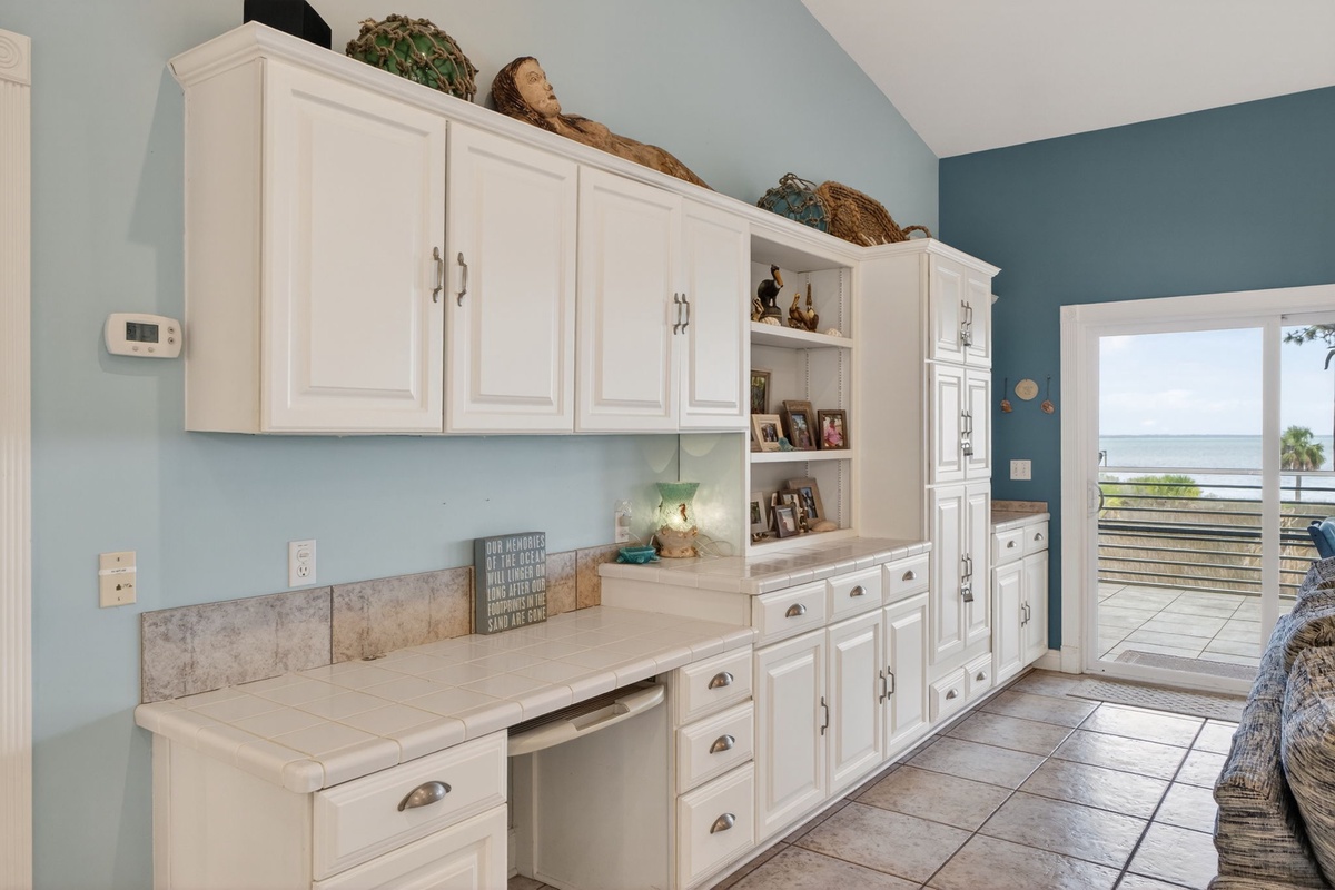 Your fully-equipped kitchen features white cabinetry and opens to stunning sea views through the patio doors.