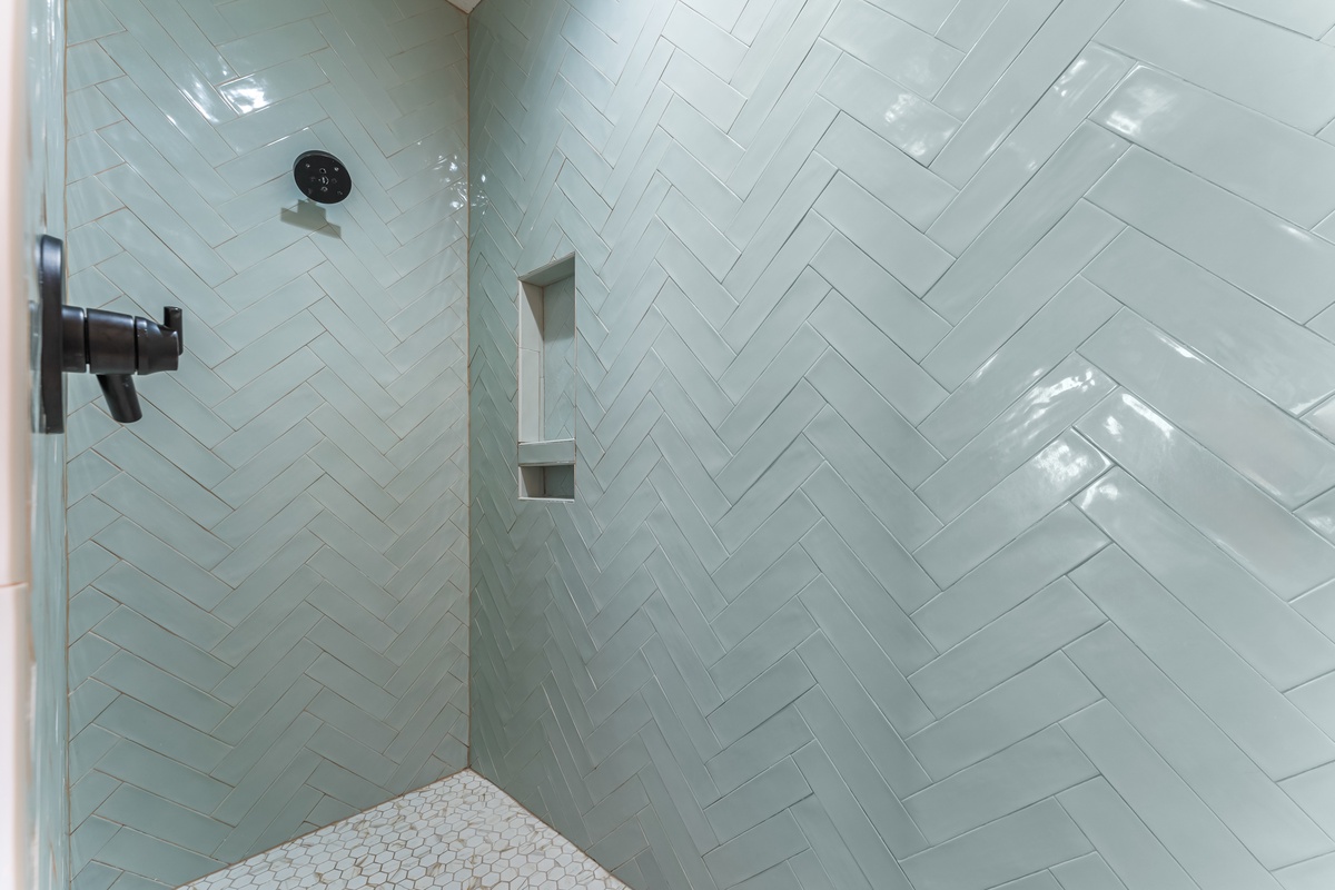 Step into your elegant walk-in shower featuring stunning herringbone tile work and modern fixtures for a refreshing start to your day.