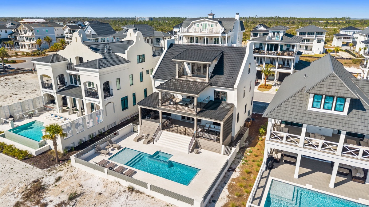 Aerial view of luxury beachfront vacation homes featuring private pools and elegant coastal architecture.