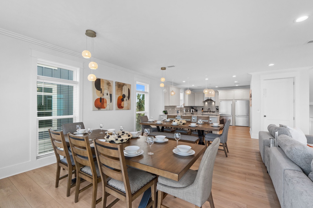 Gather around a spacious table perfect for shared meals, where soft pendant lighting creates intimate ambiance beside your modern, fully-equipped kitchen—your welcoming home away from home.