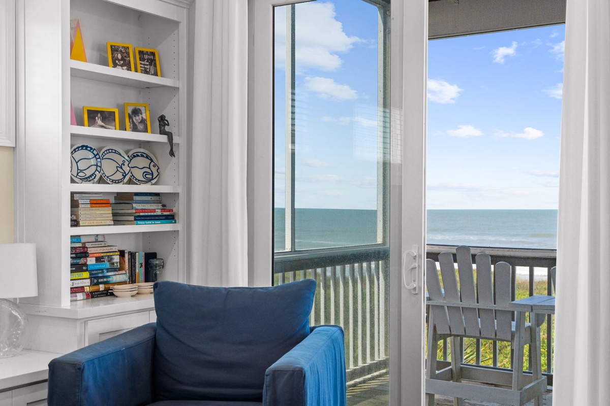 Sink into your favorite book in this cozy reading nook while the endless ocean stretches out before you—your perfect escape just beyond the glass.