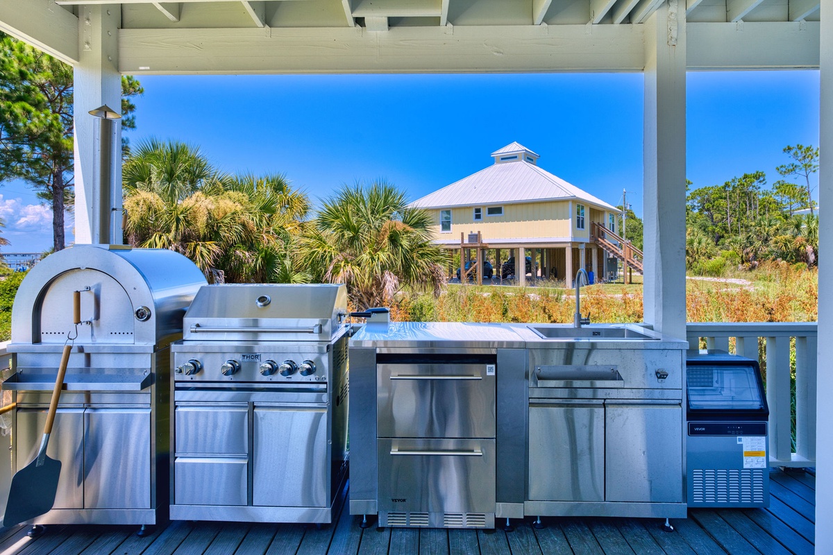 Fire up your culinary dreams in this resort-style outdoor kitchen, complete with a pizza oven, gas grill, and panoramic views of lush tropical palms and coastal homes.