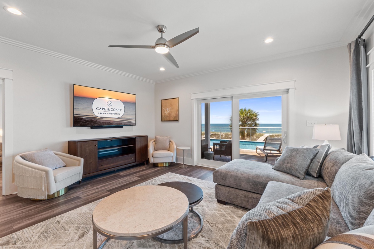 Unwind in your bright living space where coastal breezes meet comfort—soft seating, a ceiling fan, and sliding doors open to your private pool and stunning ocean views.