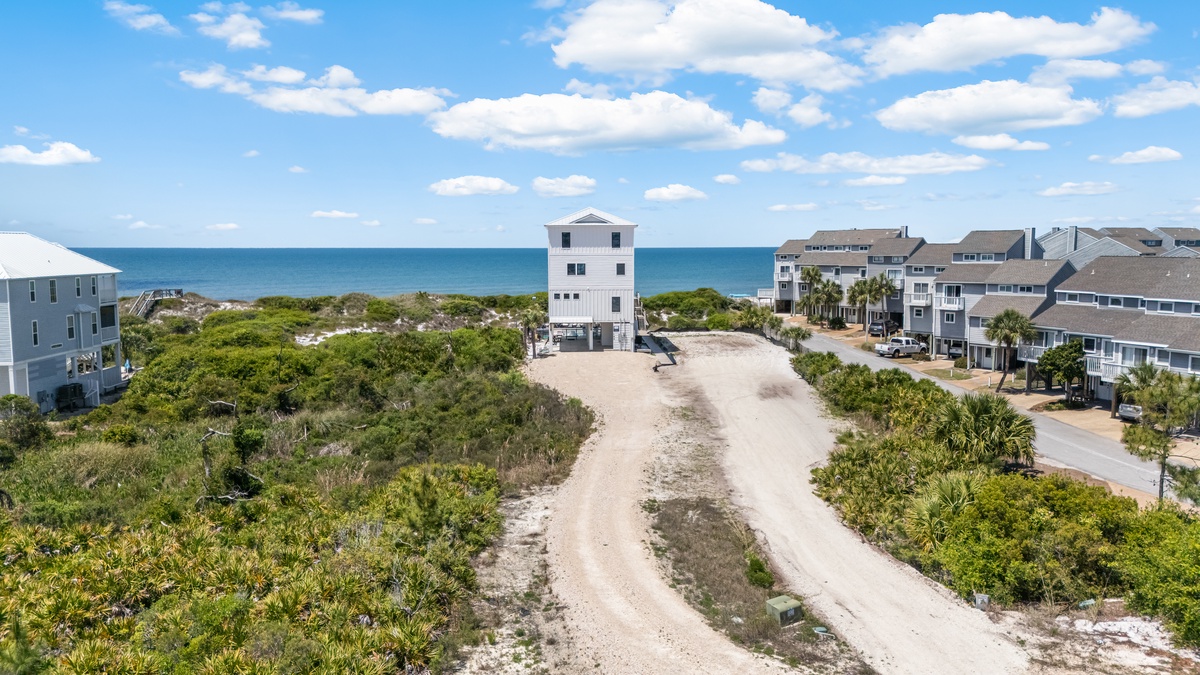 Coastal property nestled between ocean and tropical vegetation, offering elevated views and beach community setting.