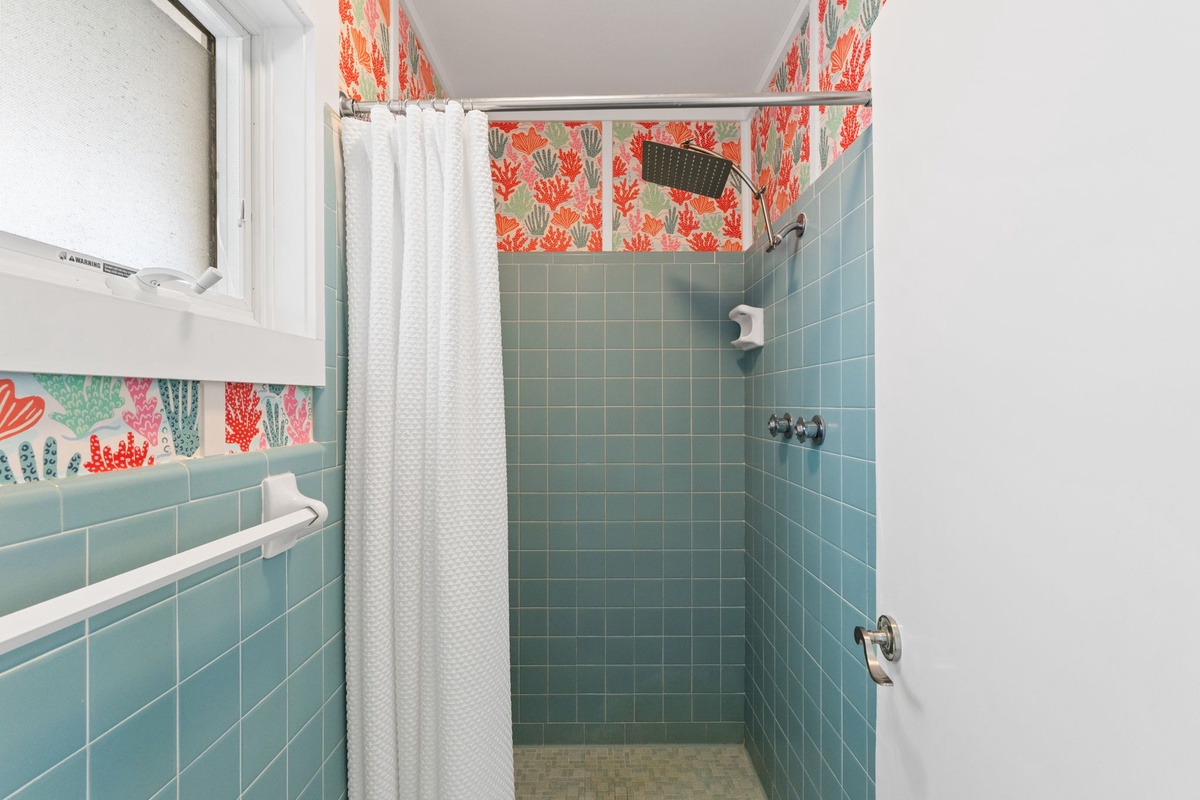 Your private bathroom features soothing aqua tile and playful coral-patterned accents, creating a cheerful coastal vibe for refreshing morning showers.
