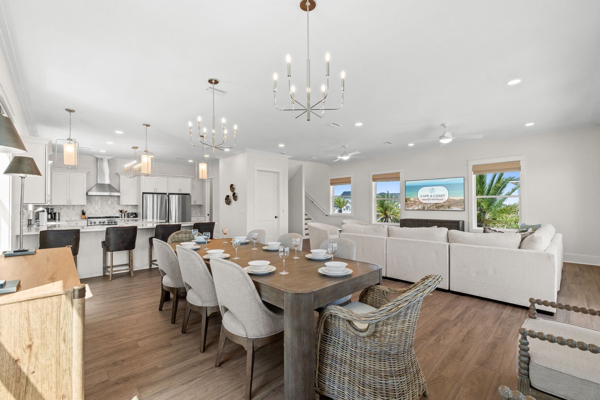 Gather around the dining table in this bright, open-concept living space where coastal charm meets modern comfort. Natural light and views of palm trees create the perfect setting to relax and make memories together.