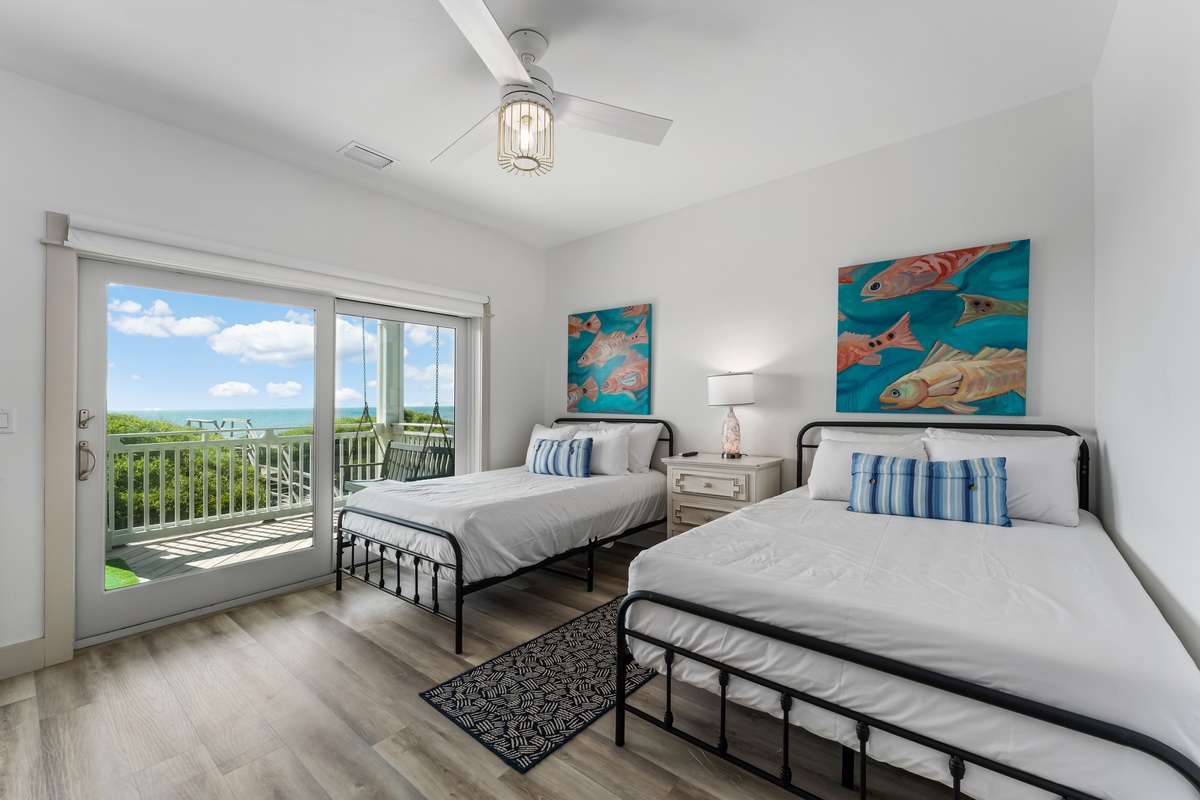 Your bright twin bedroom features ocean-themed art and private balcony access with stunning tropical views.