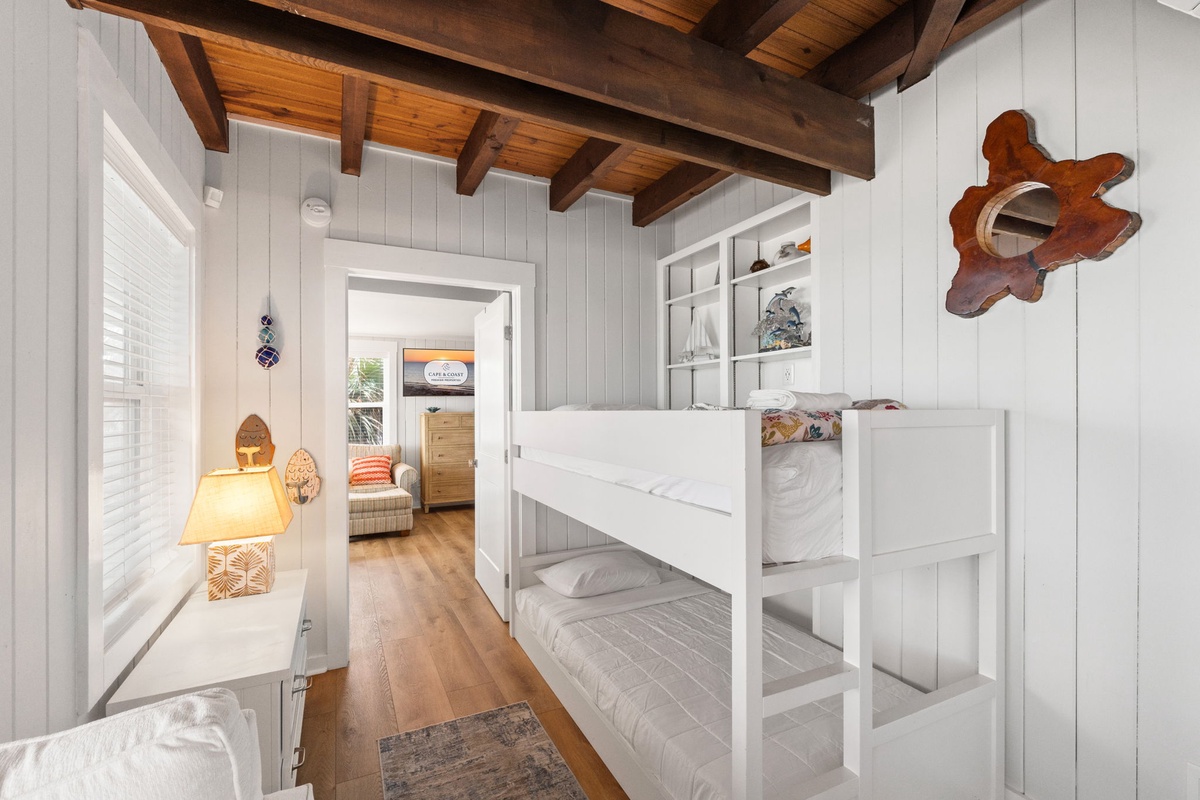 Cozy nautical-themed bunk room with exposed wood beam ceiling and beach-inspired décor—perfect for your crew to share laughs after a day exploring.