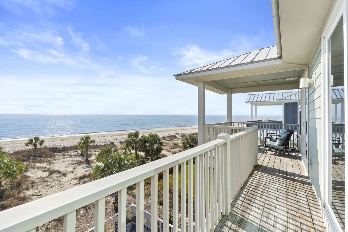 Beachfront balcony offering stunning ocean views and sandy shores stretching to the horizon.