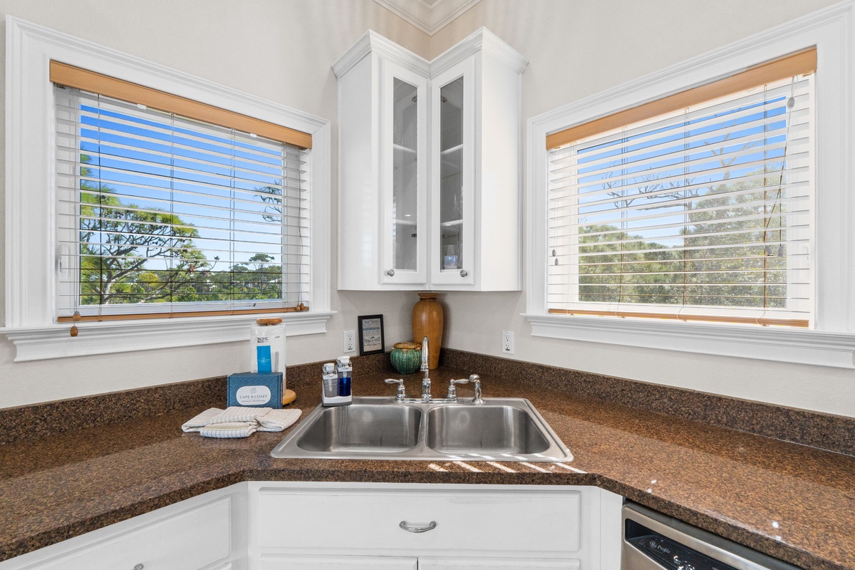 Your kitchen corner features granite counters, stainless sink, and white cabinets with glass doors. Natural light streams through blinds.