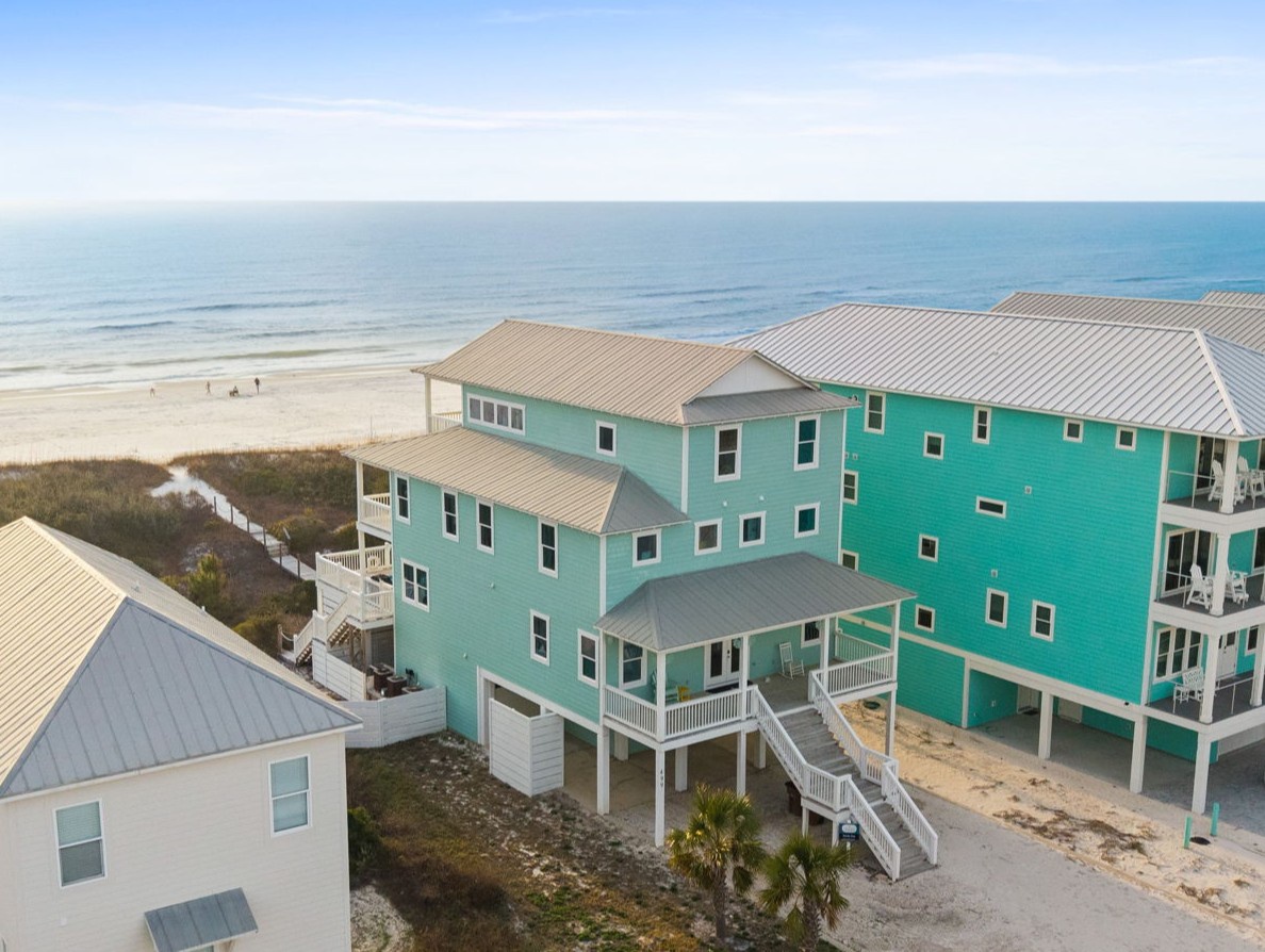 Distinctive beachfront properties showcase vibrant turquoise exteriors just steps from pristine sandy shores and rolling ocean waves.