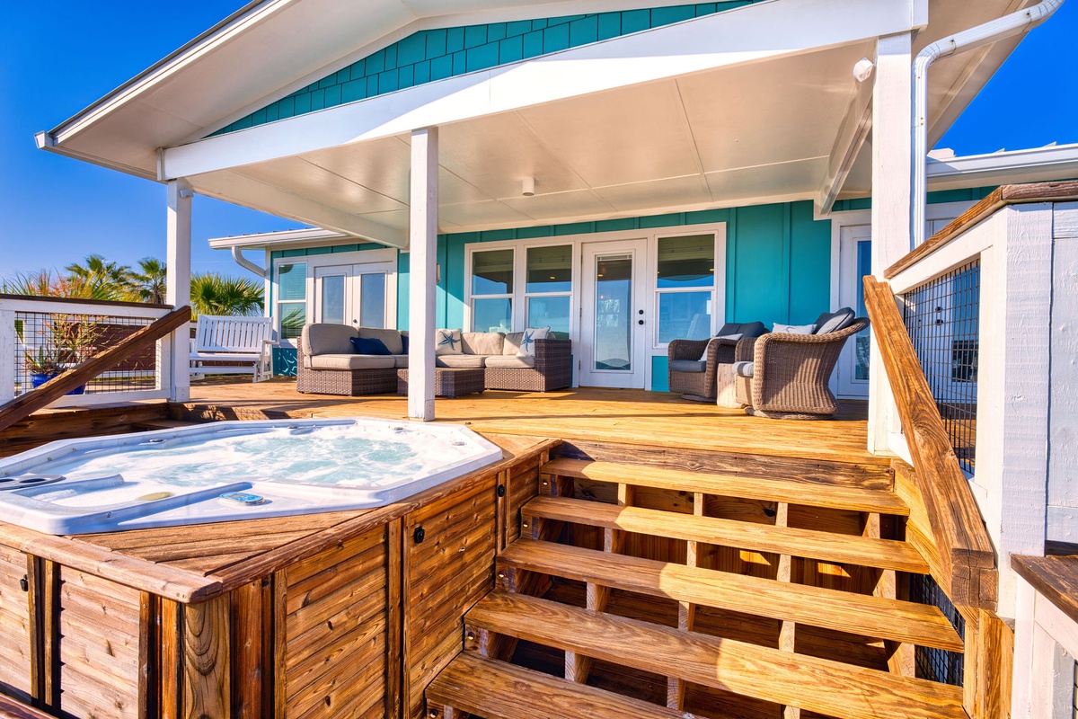 Soak in your private hot tub on this stunning deck, surrounded by comfortable seating and tropical vibes under brilliant blue skies.