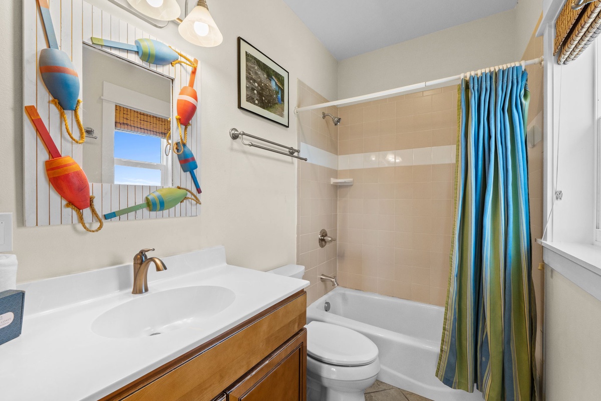 Refresh after your beach adventures in this charming coastal bathroom featuring vibrant nautical decor and a relaxing tub-shower combo.