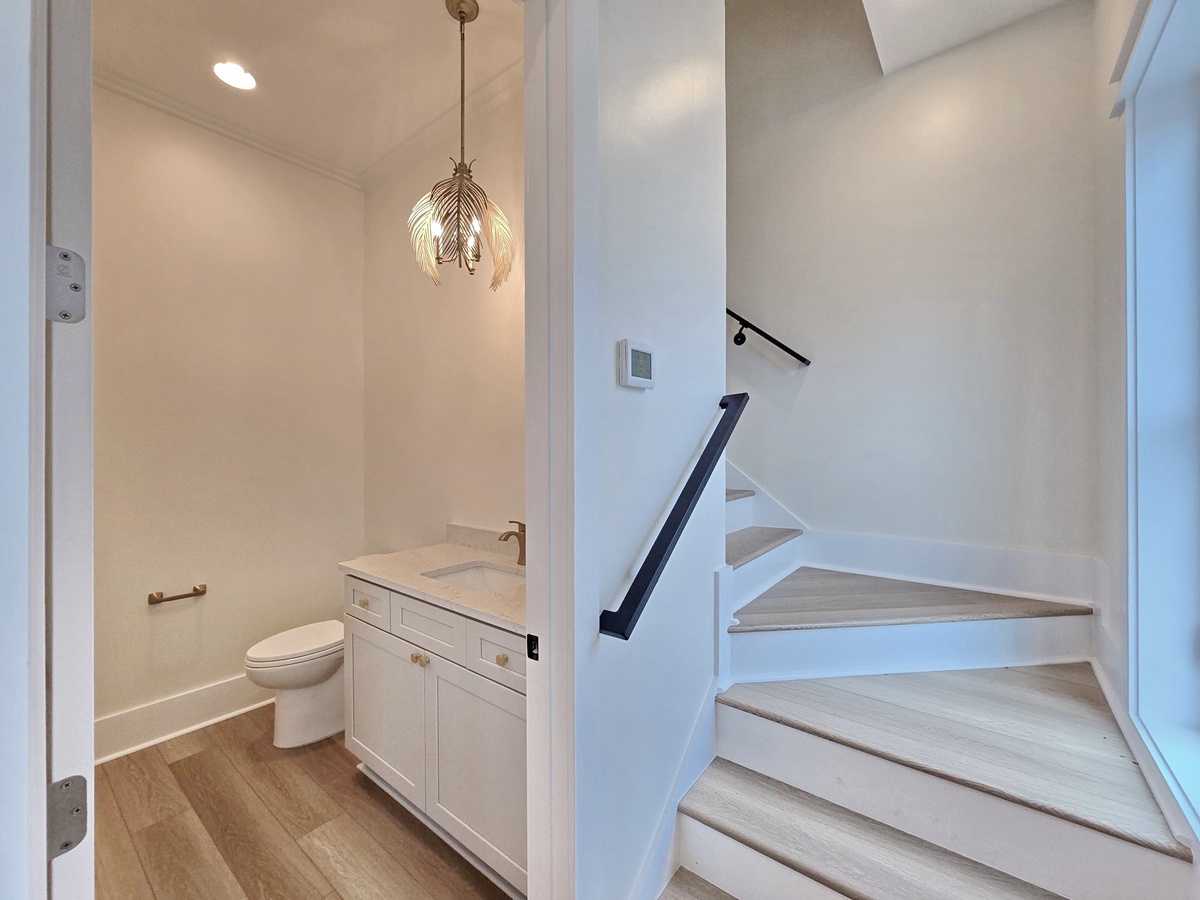 Sleek powder room with elegant pendant lighting and modern stairs create a stylish transition space for your comfort.