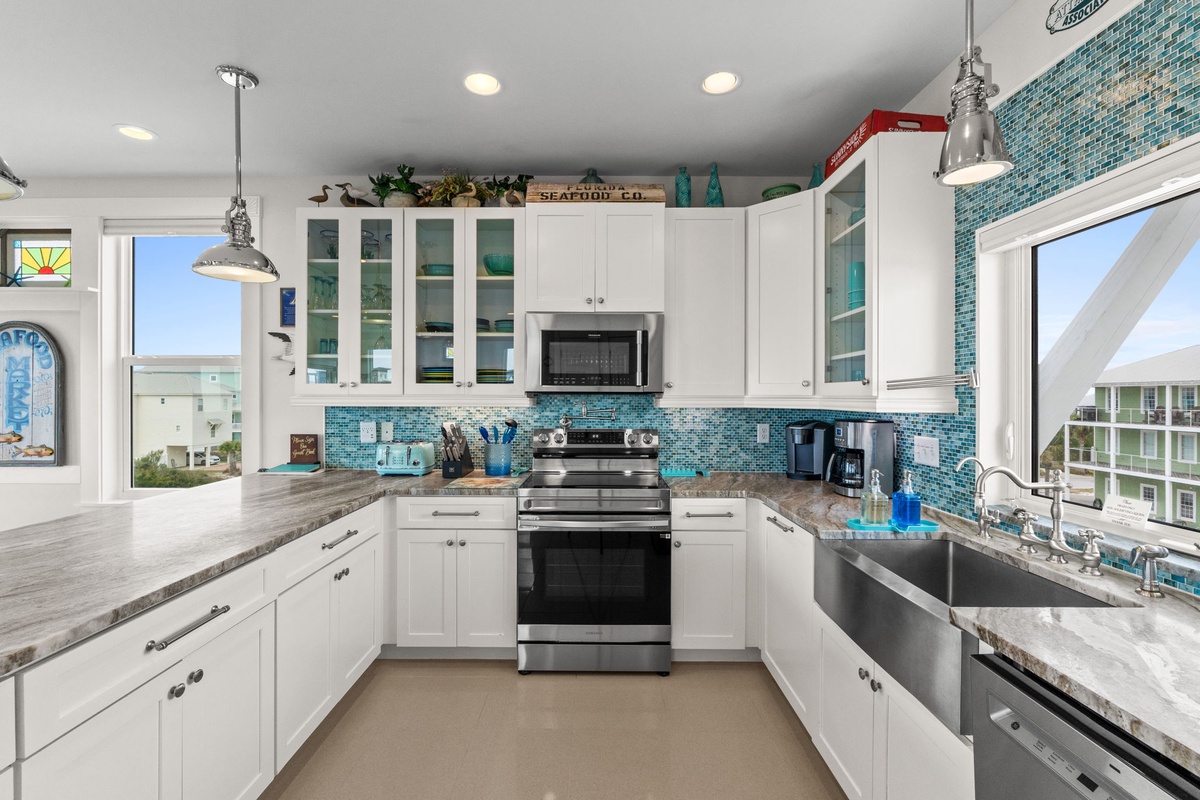Your gourmet kitchen sparkles with turquoise tile backsplash, sleek white cabinets, and modern appliances—perfect for creating memorable coastal meals.