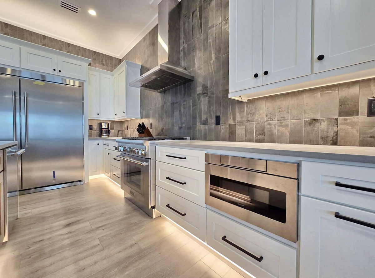 Your gourmet kitchen awaits with sleek white cabinetry, stainless steel appliances, and warm under-cabinet lighting perfect for cooking memorable meals.