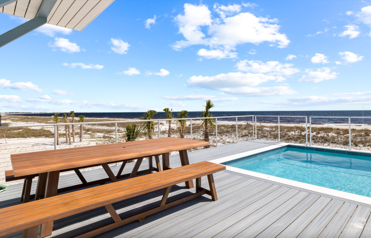 Beachfront deck with pool and dining table offering direct ocean access and stunning coastal views.