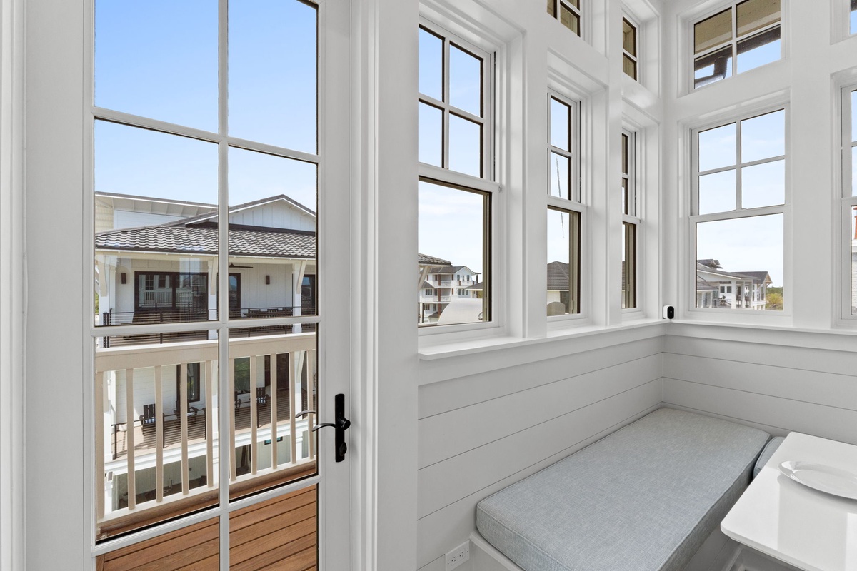 Bright sunroom with wraparound windows lets you soak in coastal neighborhood views from your cozy window seat.