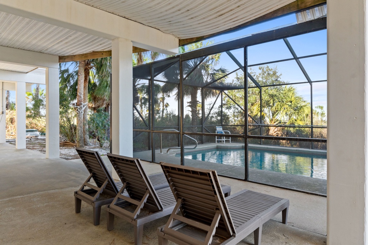 Relax on comfortable loungers beside your private screened pool, where tropical palms create a serene backdrop for your perfect getaway.