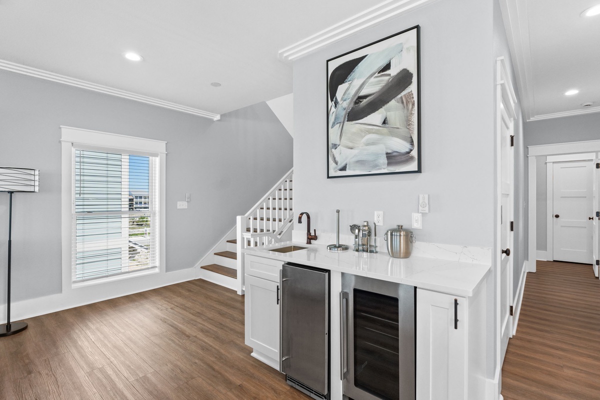 Sleek wet bar with wine cooler and mini fridge awaits your evening toast, while contemporary artwork and gleaming countertops set an elegant, inviting mood.