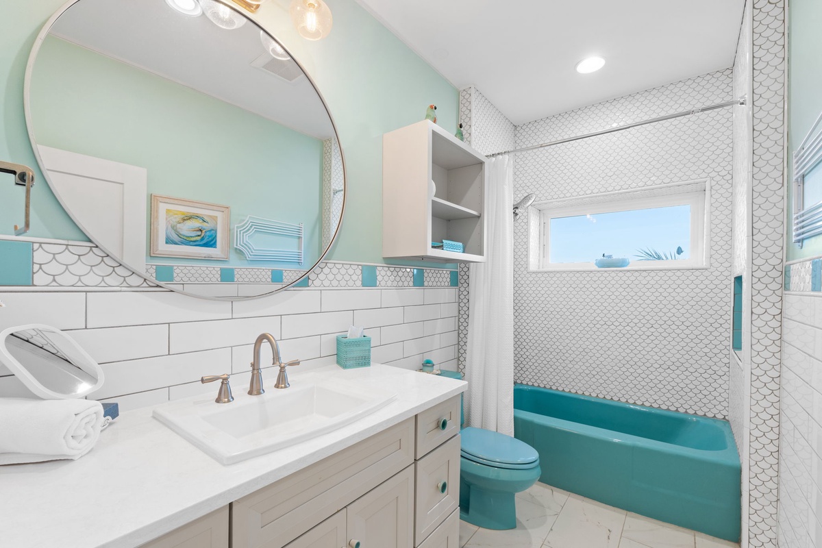 Step into your refreshing private bathroom featuring a soaking tub, modern fixtures, and charming coastal-inspired turquoise accents.