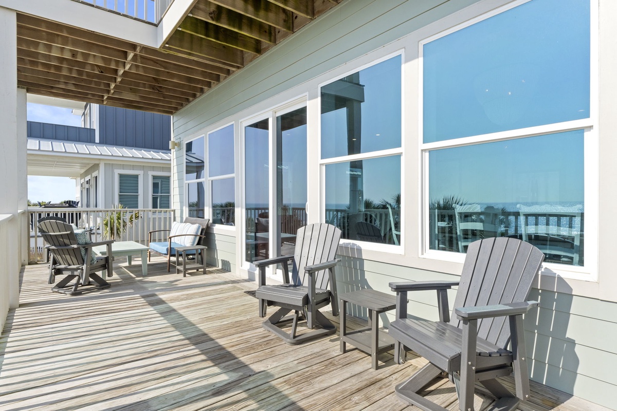 Relax on your private deck with comfortable Adirondack chairs, soaking up coastal sunshine while enjoying beautiful water views through oversized windows.