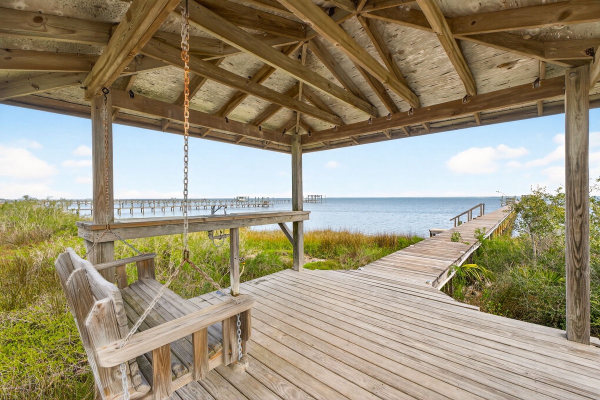 Relax on your private covered deck with waterfront views, featuring a charming swing where you can unwind while watching boats drift by the peaceful marina.