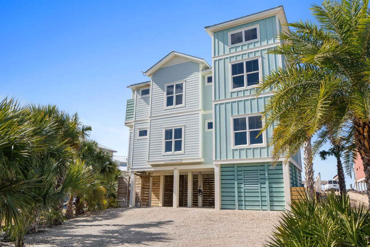Coastal beach house with tropical landscaping and elevated design in sunny waterfront neighborhood.
