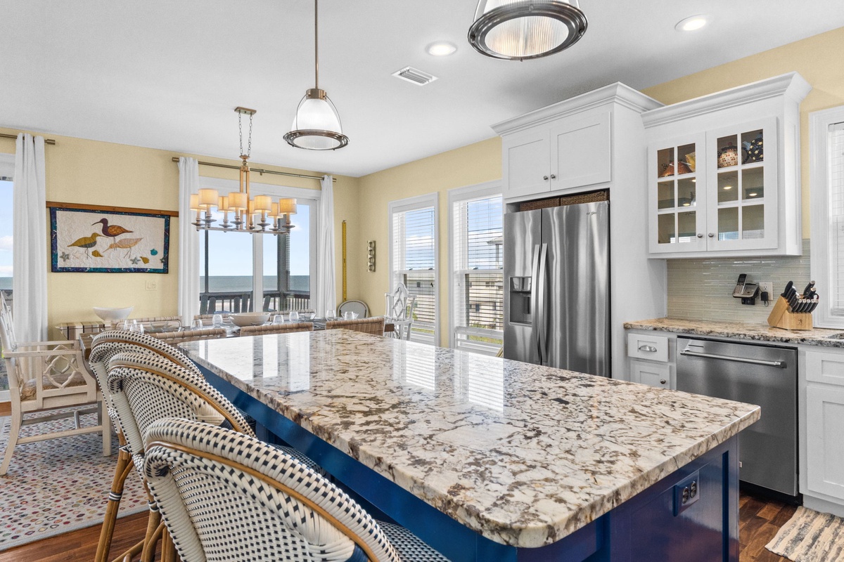 Your spacious, light-filled kitchen invites you to gather around the gleaming granite island—perfect for morning coffee or prepping meals while taking in stunning water views through the windows.