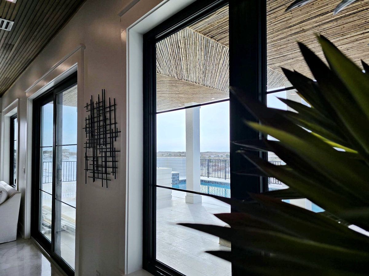 Modern interior with floor-to-ceiling windows offering stunning pool and water views, complemented by stylish décor and natural elements.