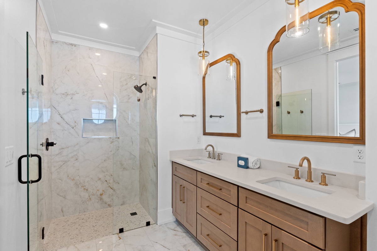 Luxe marble surrounds you in this spa-like dual-vanity bathroom, complete with a spacious walk-in shower and elegant gold fixtures for your ultimate comfort.