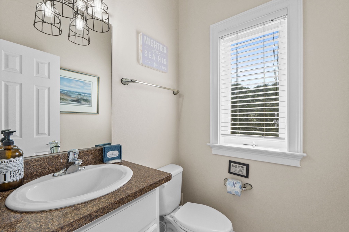 Your private powder room features coastal charm with nautical touches and natural light streaming through crisp white blinds.