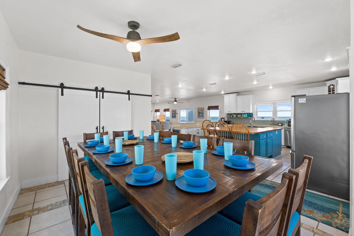 Gather around the expansive dining table where meals become memories, with ocean breezes flowing through and bright blue place settings awaiting your group's arrival.