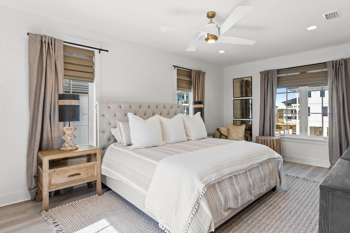 Unwind in your serene master bedroom featuring a plush tufted headboard, premium linens, and panoramic windows filling the space with natural light.