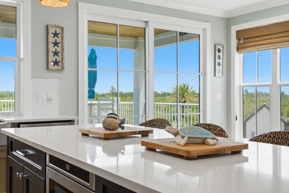 A bright kitchen island opens onto your private balcony, with lush views and coastal-inspired décor that make meal prep feel like a mini vacation.