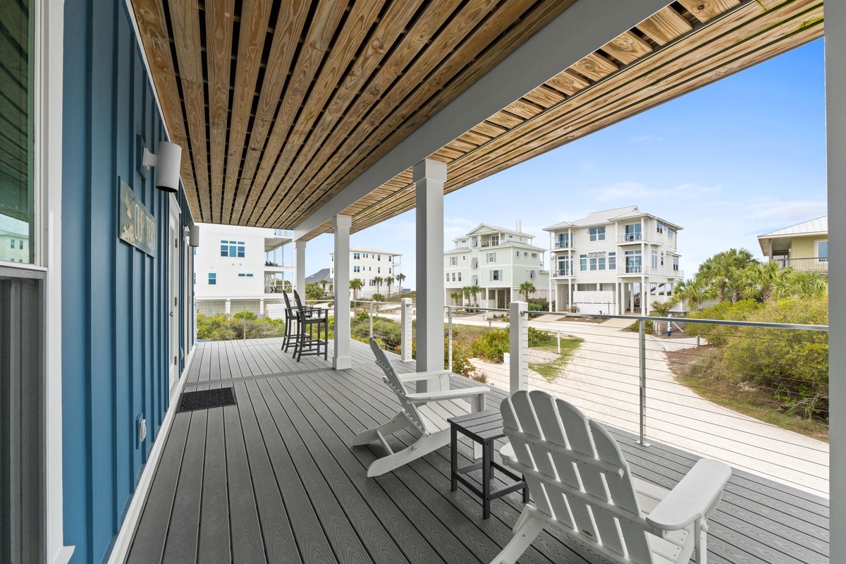 Relax on your private deck with coastal views, where comfortable seating awaits under the stylish pergola's shade.