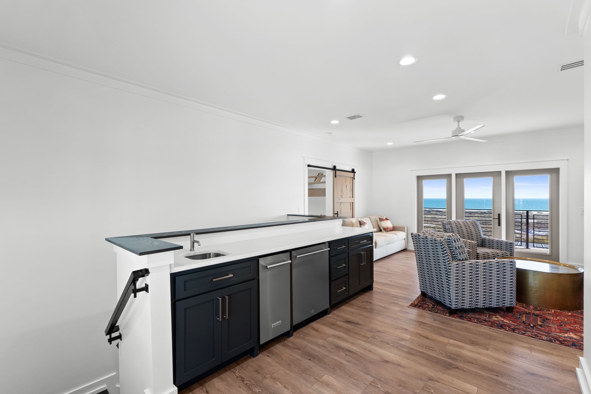 Your modern kitchen opens to breathtaking ocean views through expansive windows, creating the perfect space for cooking while watching waves roll in.