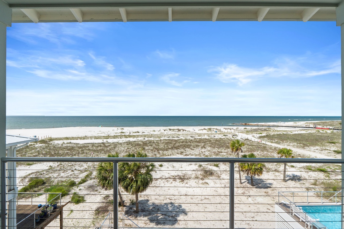 Stunning beachfront views extend from this covered balcony, showcasing white sand, turquoise waters, and coastal palms stretching along the shoreline. A perfect spot to unwind and soak in the scenery.